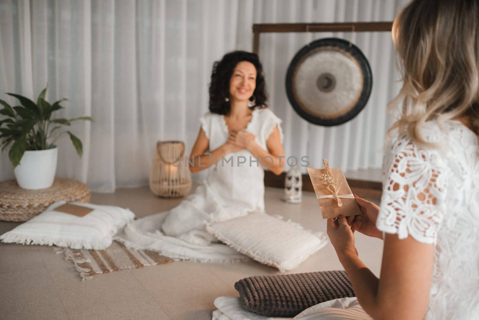 A woman in white clothes passes an envelope with a wish to another woman. The concept of the women's circle.