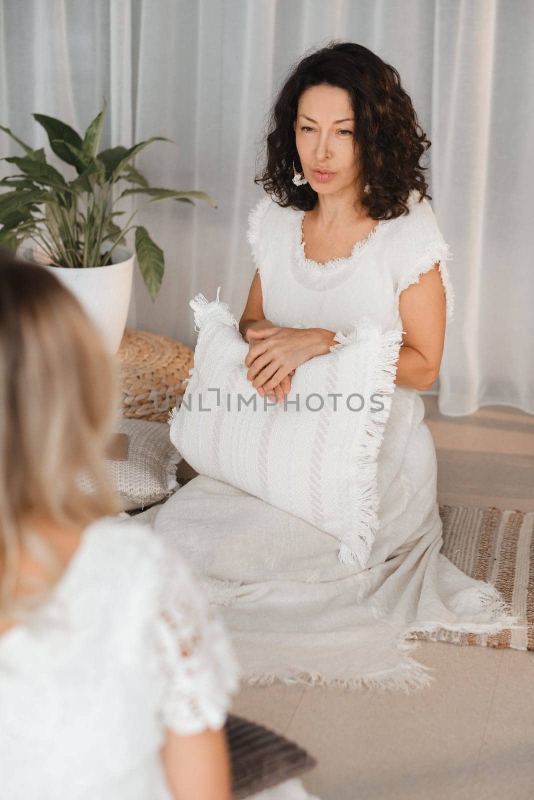 Two women practice yoga sitting opposite each other.