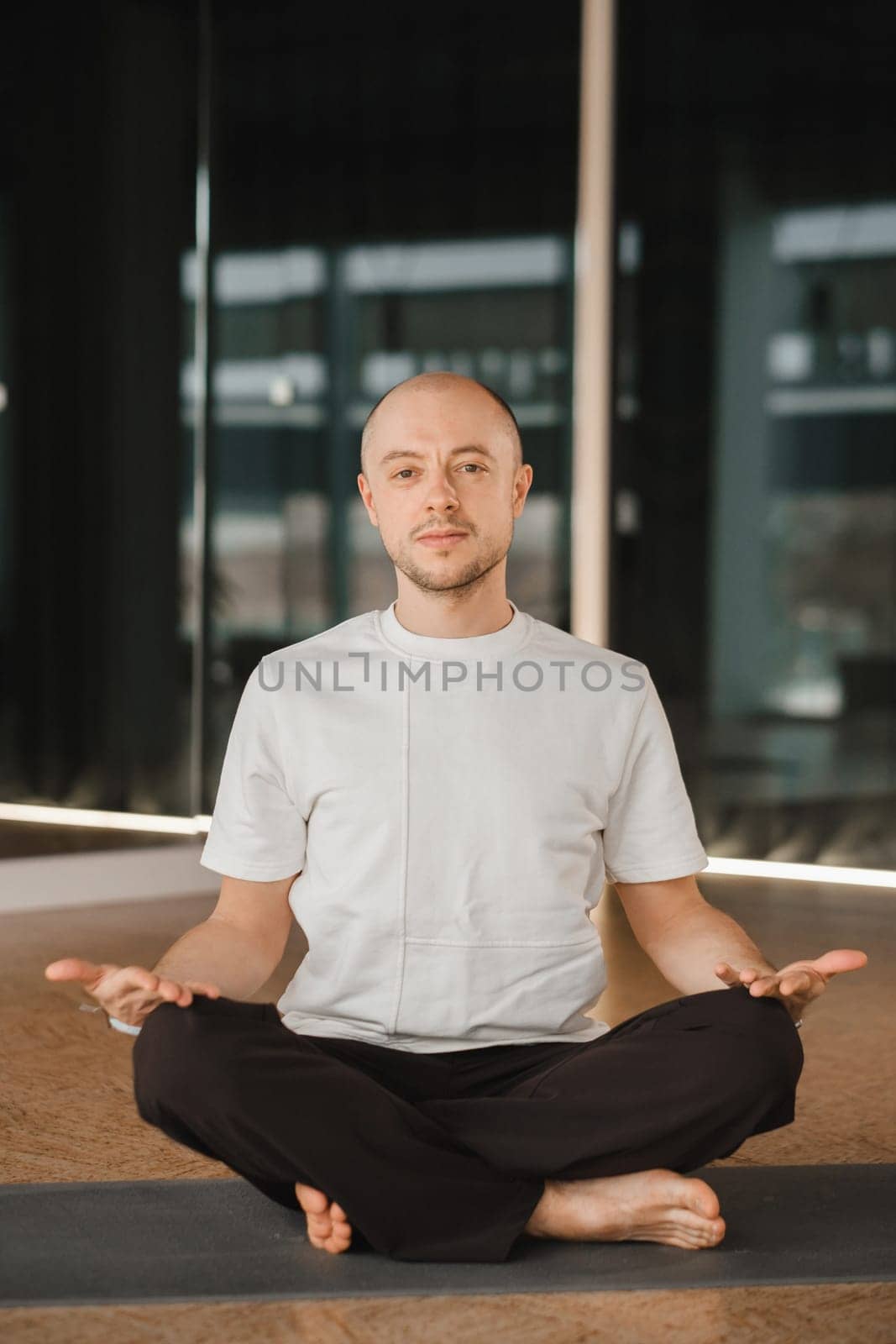 An athletic young man does exercises in the fitness room. A professional guy does yoga in the gym by Lobachad