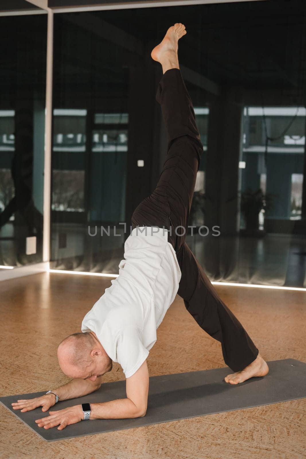 An athletic young man does exercises in the fitness room. A professional guy does yoga in the gym.