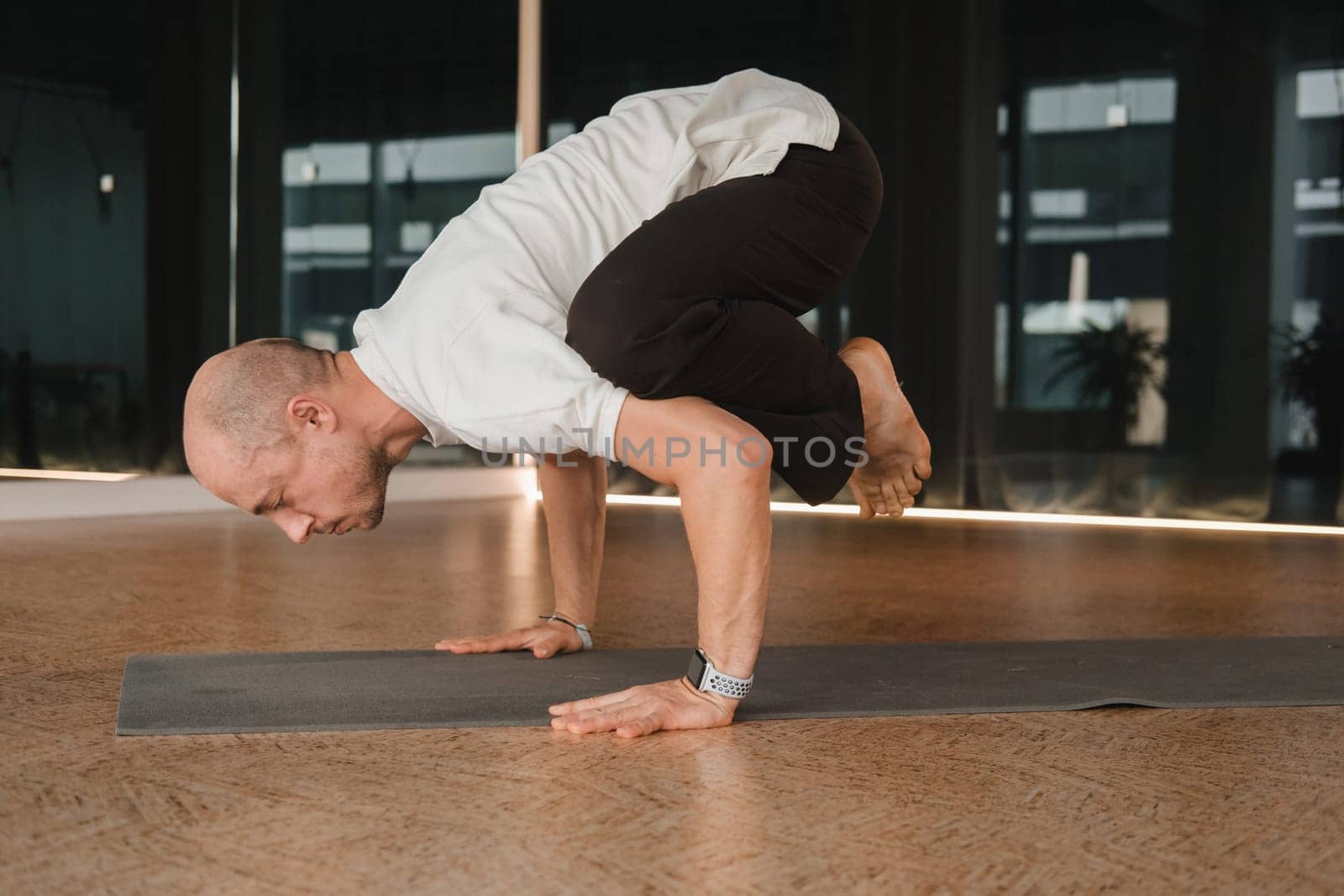 An athletic young man does exercises in the fitness room. A professional guy does yoga in the gym by Lobachad