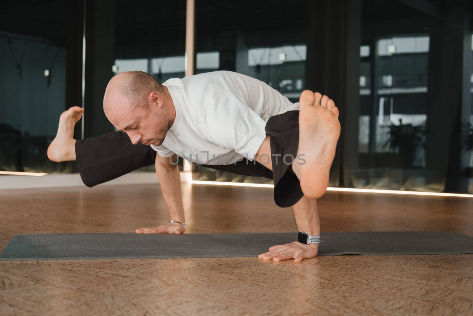 An athletic young man does exercises in the fitness room. A professional guy does yoga in the gym by Lobachad