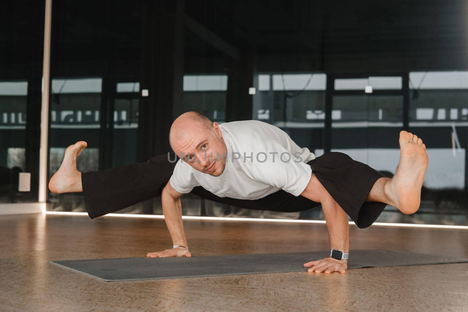 An athletic young man does exercises in the fitness room. A professional guy does yoga in the gym.