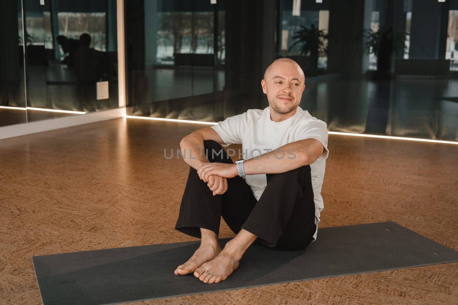 An athletic young man does exercises in the fitness room. A professional guy does yoga in the gym by Lobachad