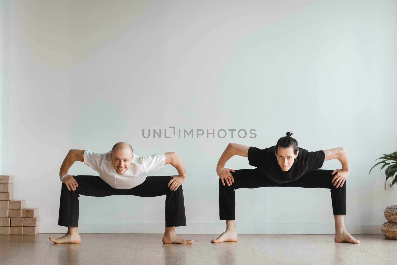 two young athletes practice yoga in the gym. Joint training, indoors, studio. The concept of a healthy lifestyle.