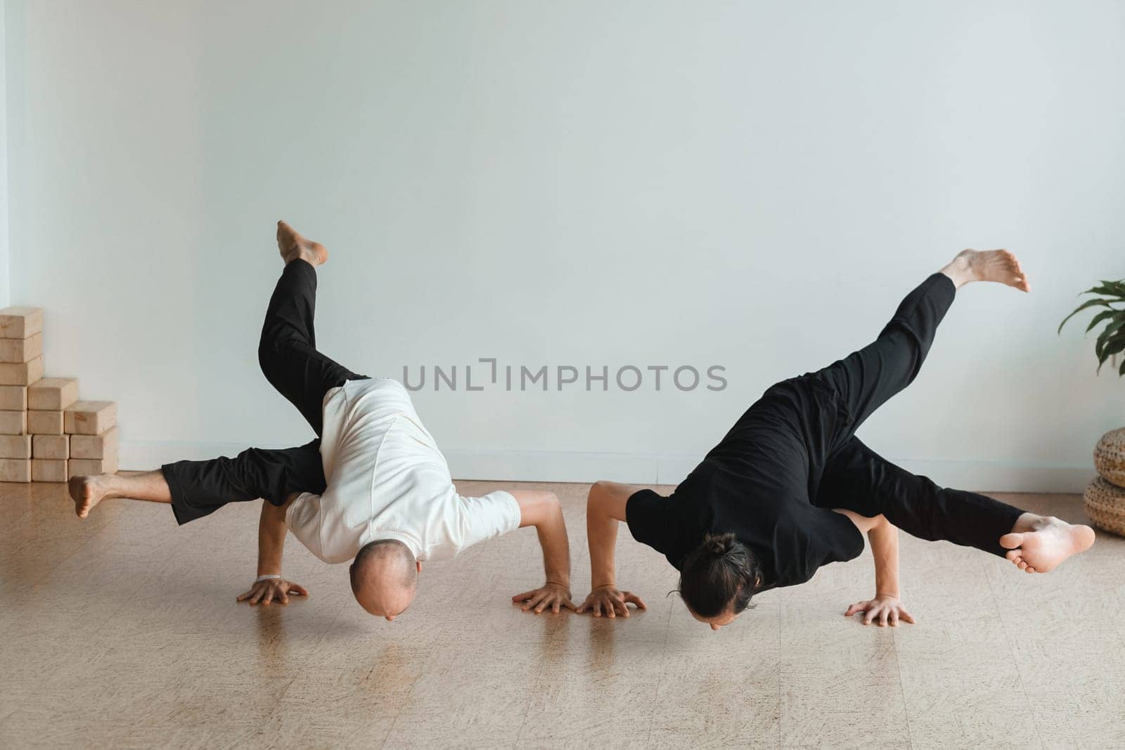 two young athletes practice yoga in the gym. Joint training, indoors, studio. The concept of a healthy lifestyle by Lobachad