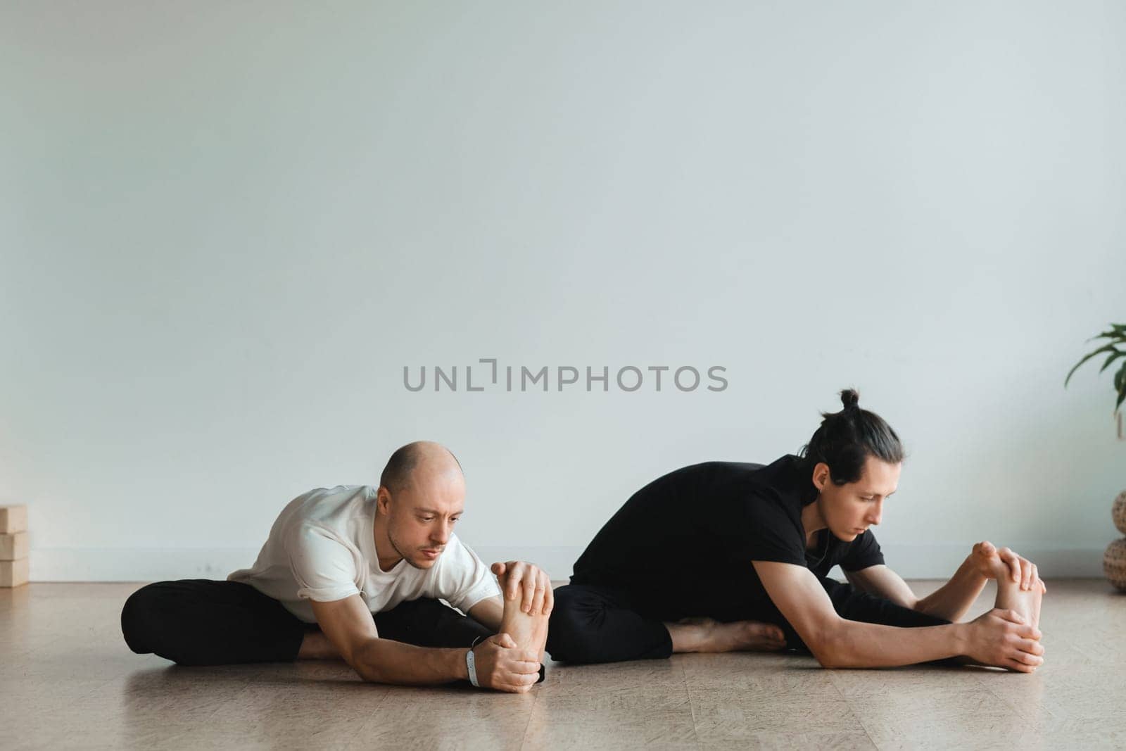 two young athletes practice yoga in the gym. Joint training, indoors, studio. The concept of a healthy lifestyle by Lobachad