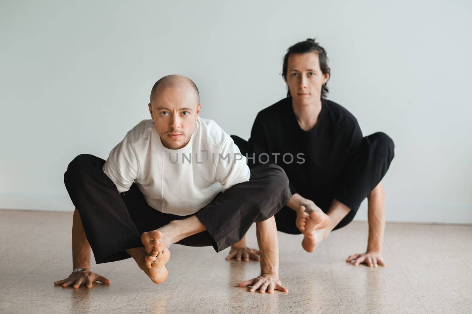 two young athletes practice yoga in the gym. Joint training, indoors, studio. The concept of a healthy lifestyle by Lobachad