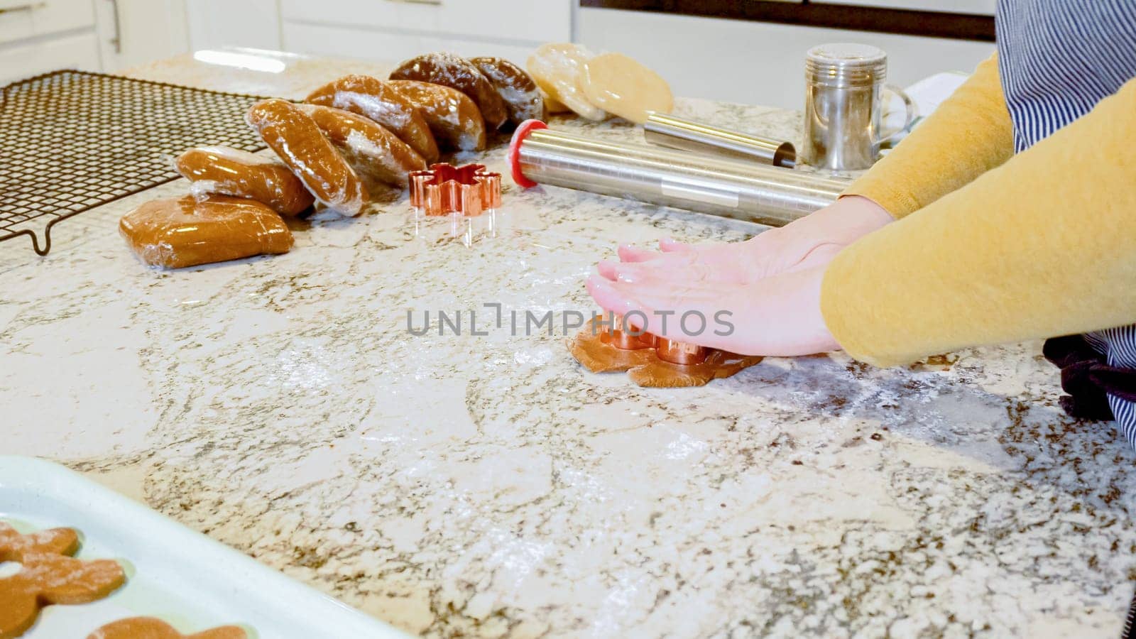 Using an adjustable rolling pin to roll out gingerbread cookie dough on the elegant marble counter in a modern kitchen, getting ready for festive holiday baking.