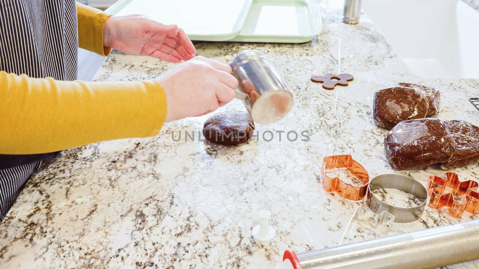 Using an adjustable rolling pin to roll out gingerbread cookie dough on the elegant marble counter in a modern kitchen, getting ready for festive holiday baking.