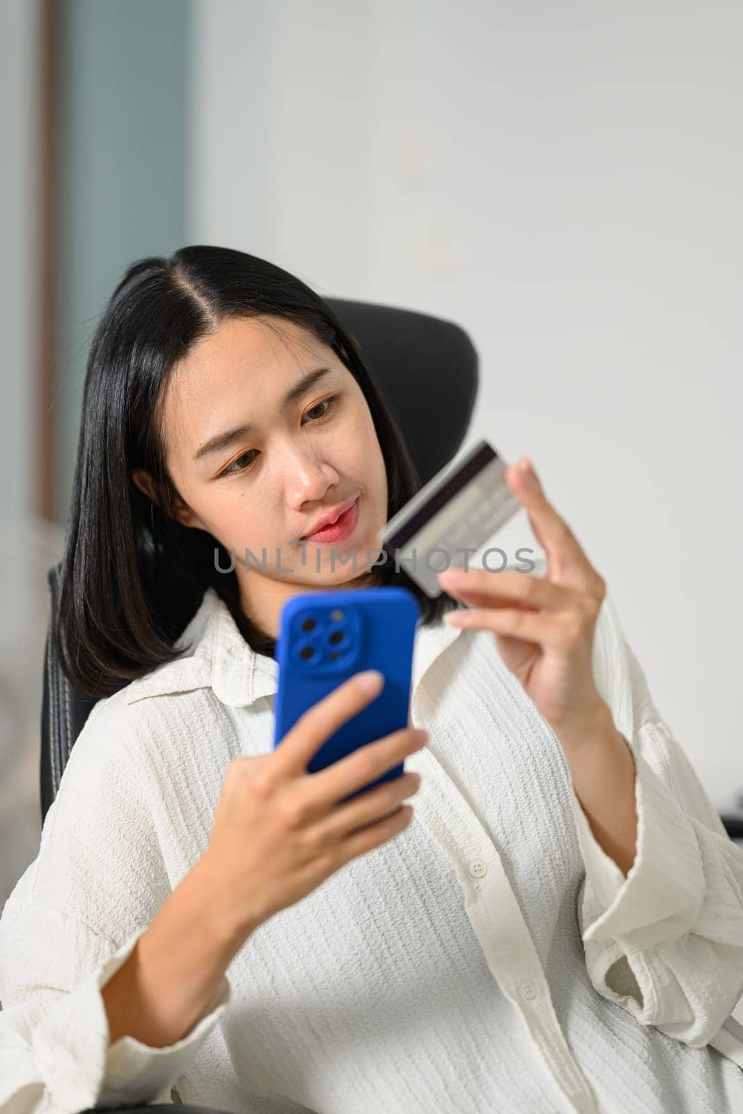 Portrait of pretty young woman holding credit card making payment on smartphone by prathanchorruangsak
