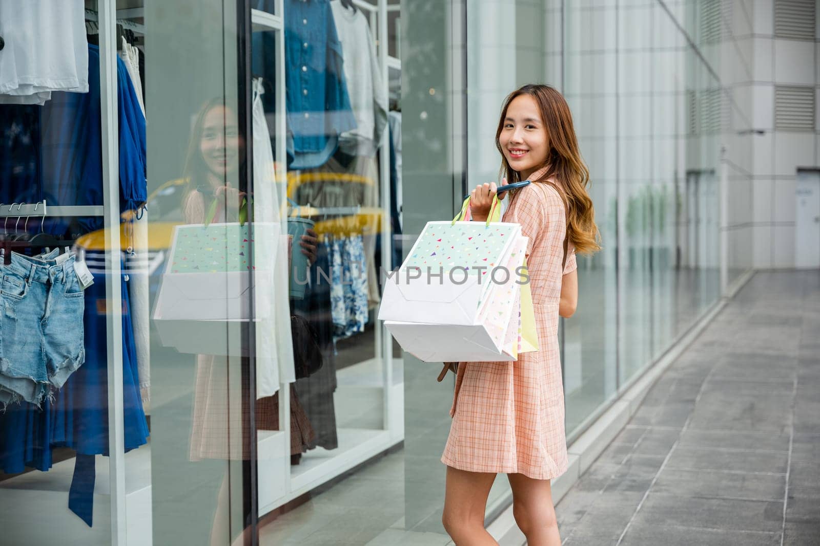 stylish shopper walks out of a clothing store, bags in hand, enjoying her shopping by Sorapop