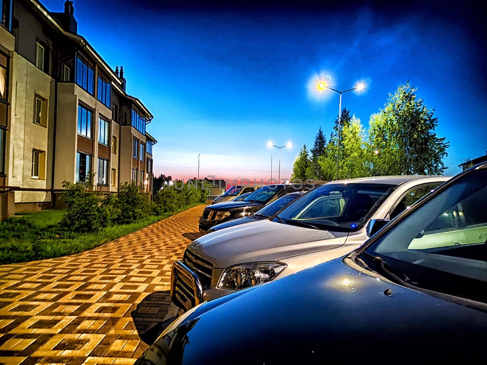 Night, village, houses and cars in the parking lot. Photography is like a painting. Serene Village Nightfall With Parked Cars and Illuminated Homes by keleny