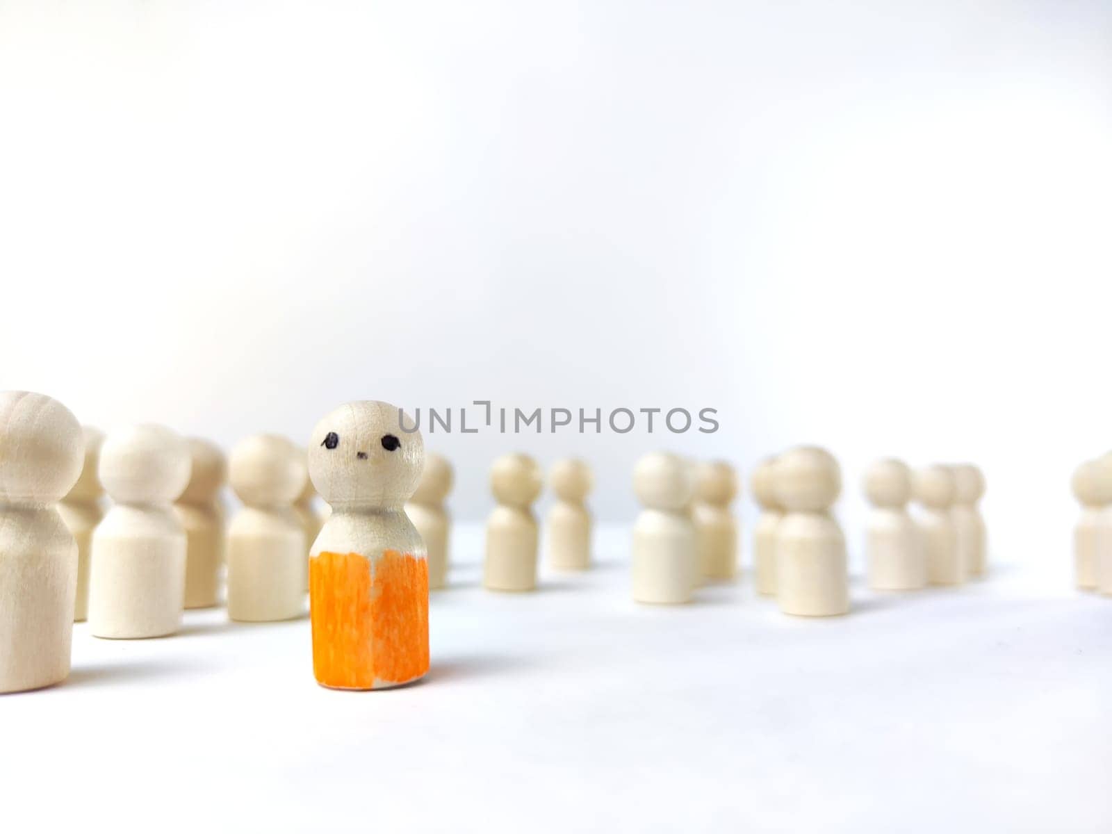 Wooden figurines with a leader and group with partial focus. The concept of distinguishing a leader from the crowd. Sighted, intelligent, different among the blind group