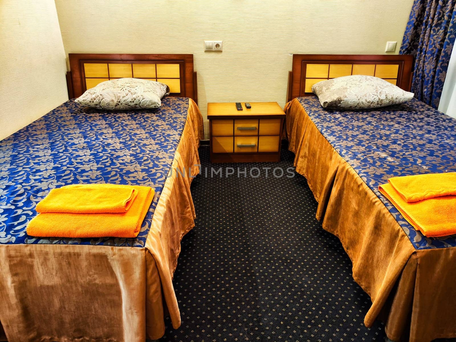 Twin Beds in a Cozy Hotel Room. Two single beds with blue bedding and orange towels in a hotel room by keleny