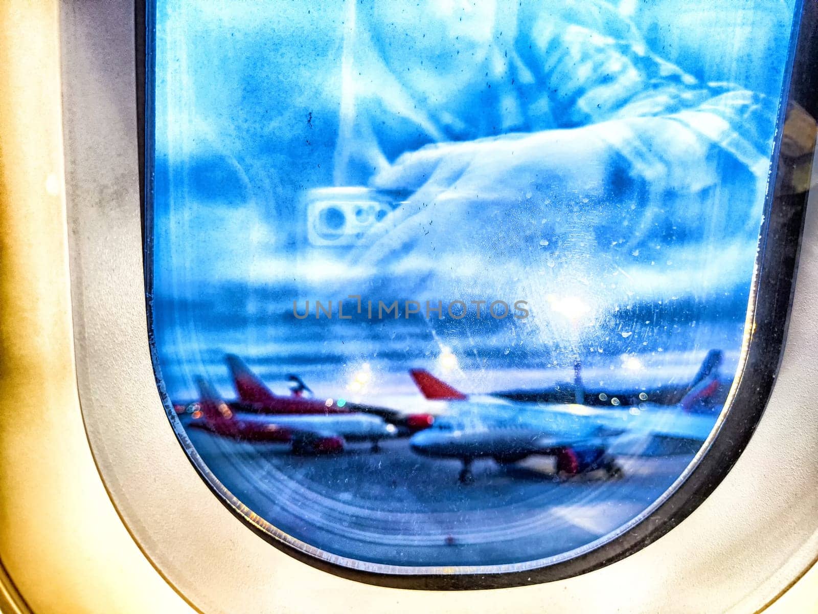 View of the planes at the airport. Airplanes on Tarmac Seen Through Airplane Window at Dusk. Airplanes lined up. Blurred by keleny