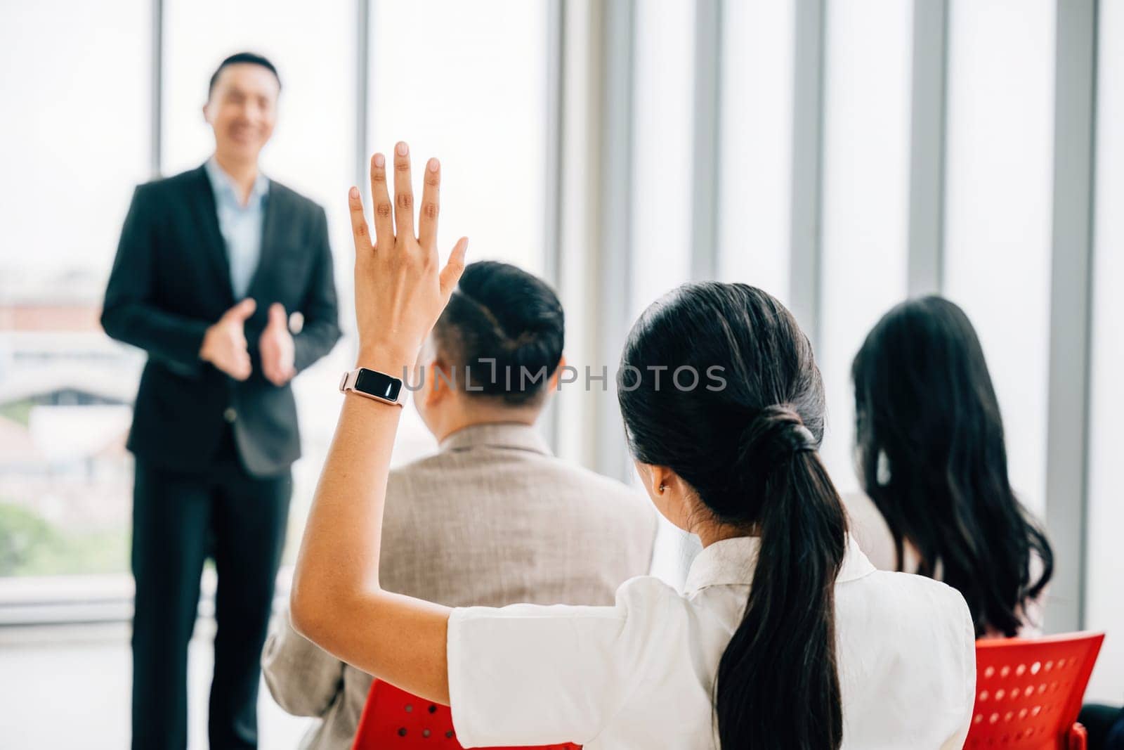 Audience engagement at a conference as hands are raised for questions, signifying the interactive nature of the meeting. A diverse group participates in a workshop or seminar presentation.