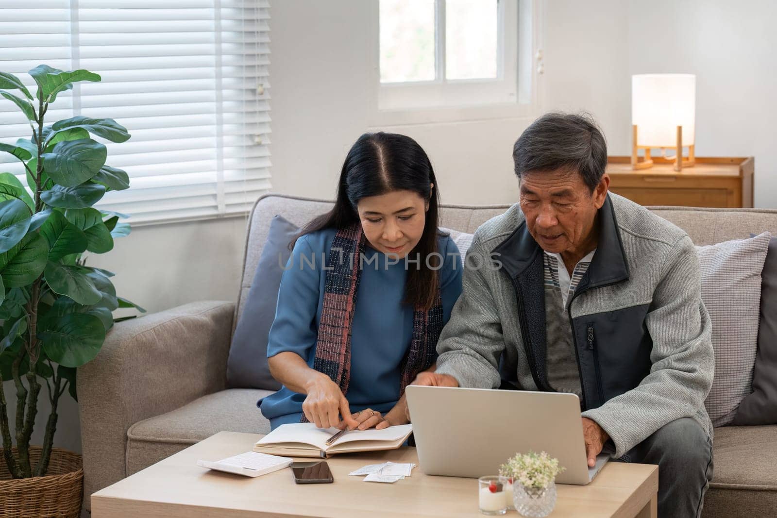 married retired senior couple checking and calculate financial billing together on sofa by itchaznong