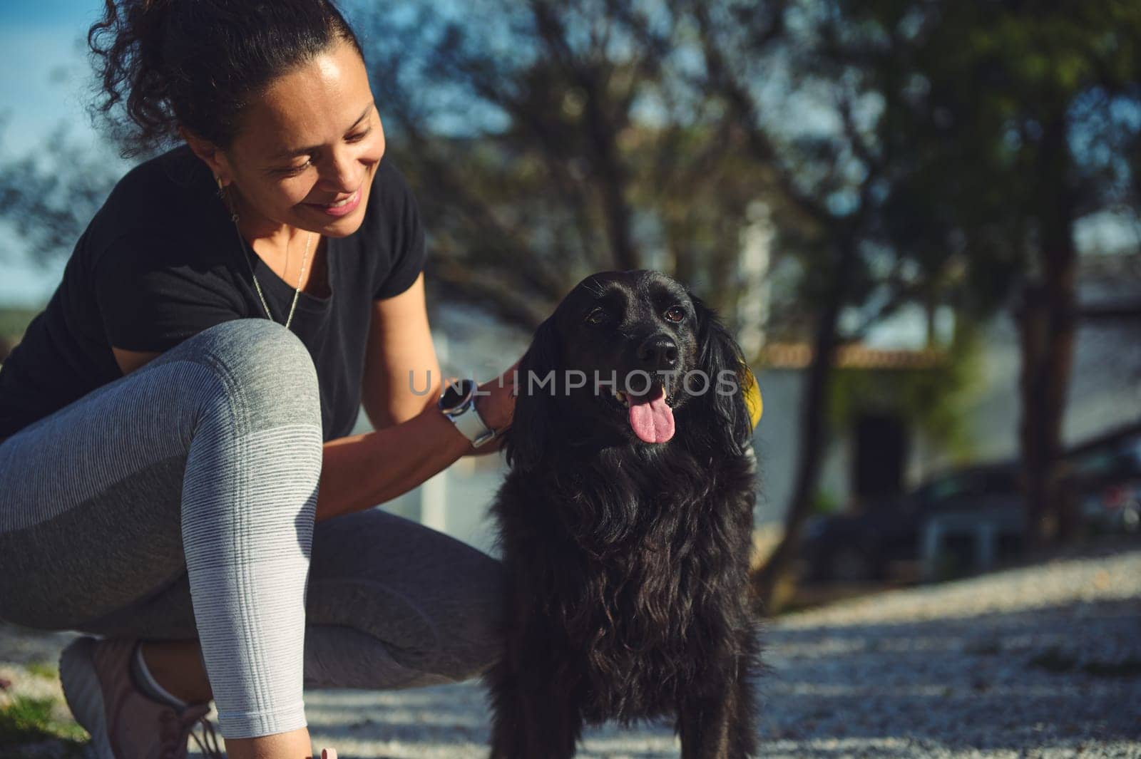 Young pretty woman having fun spending time with her pet outdoors, walking her playful cocker spaniel dog on the nature. Playing pets, pet concept.