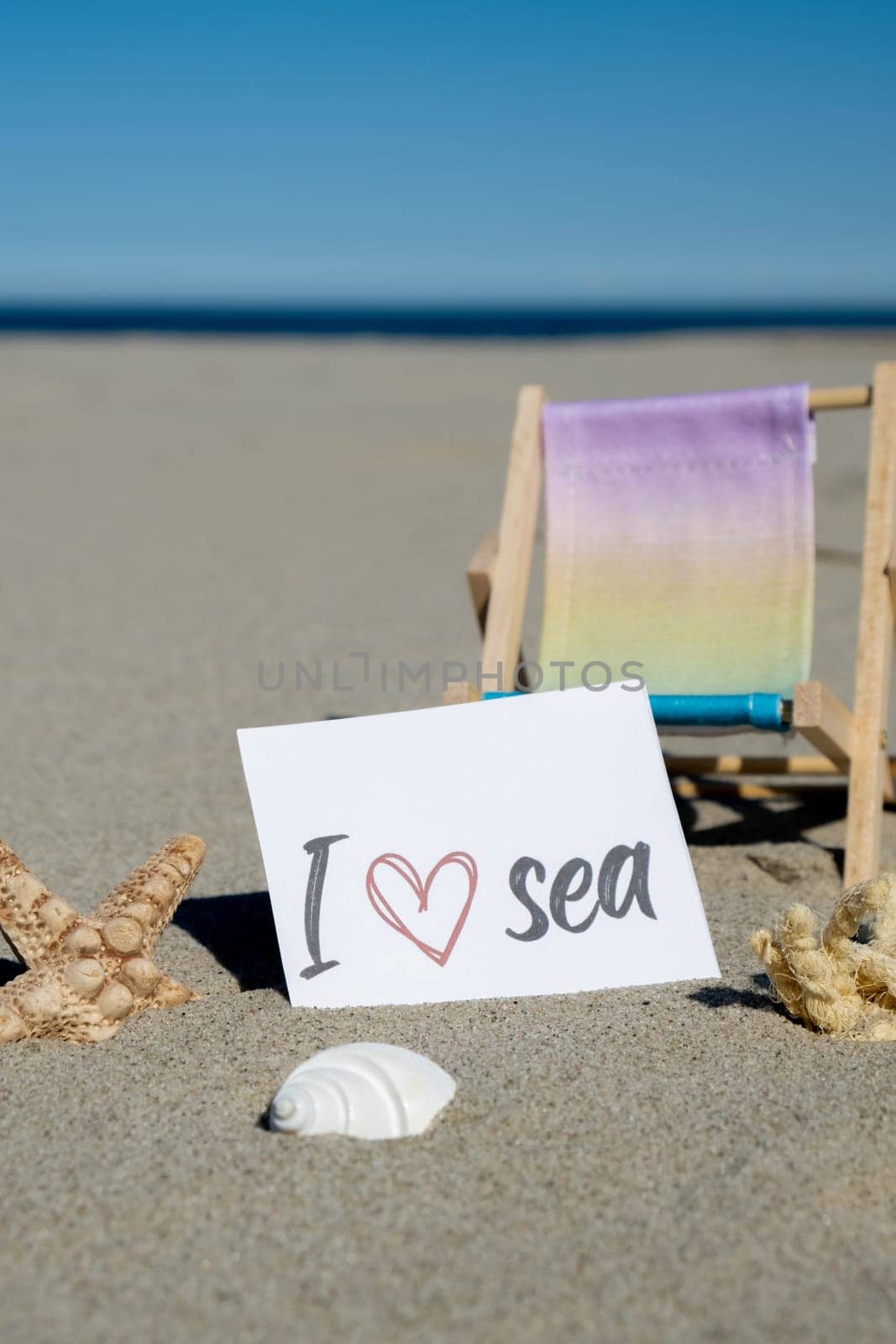 I LOVE SEA text on paper greeting card on background of beach chair lounge starfish summer vacation decor. Sandy beach sun coast. Holiday concept postcard. Travel by anna_stasiia