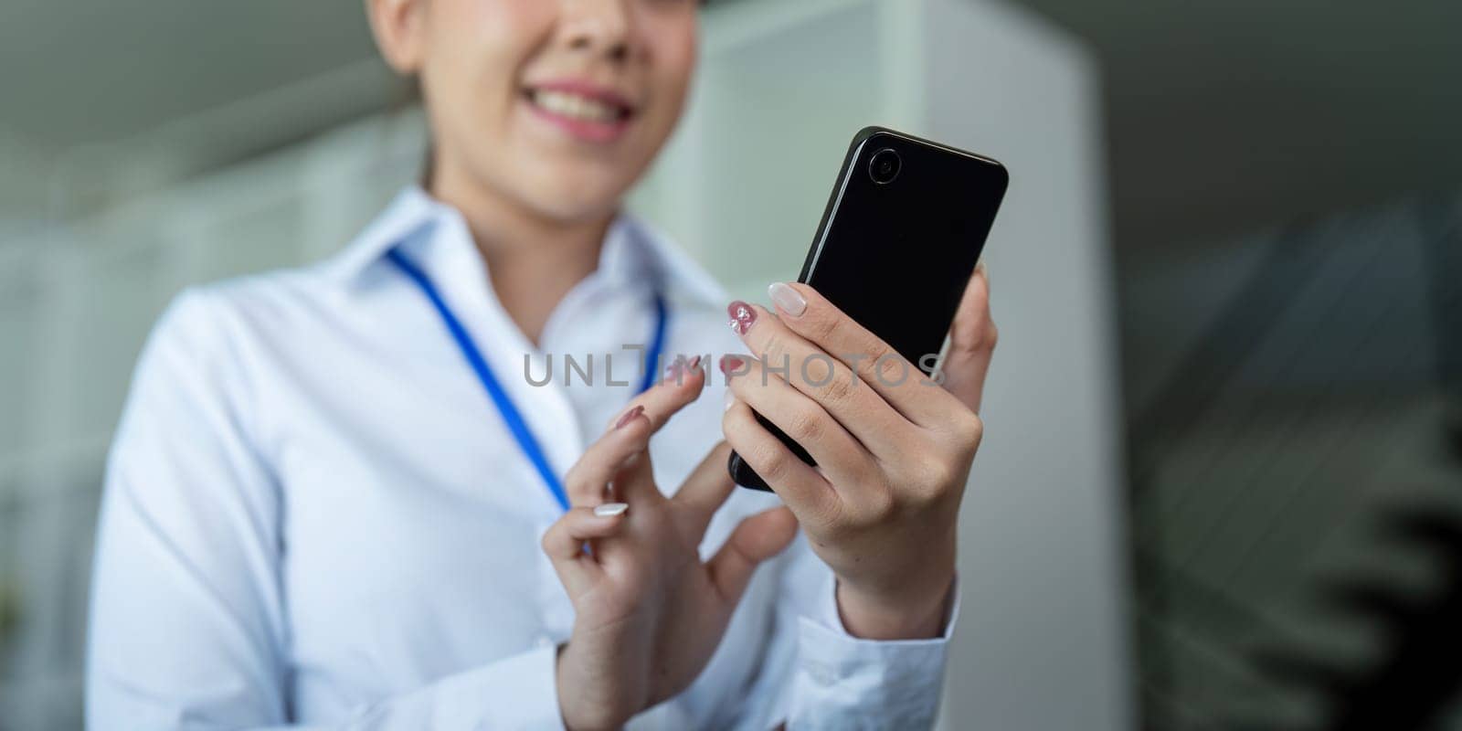 Businesswoman holding and using mobile phone in office.