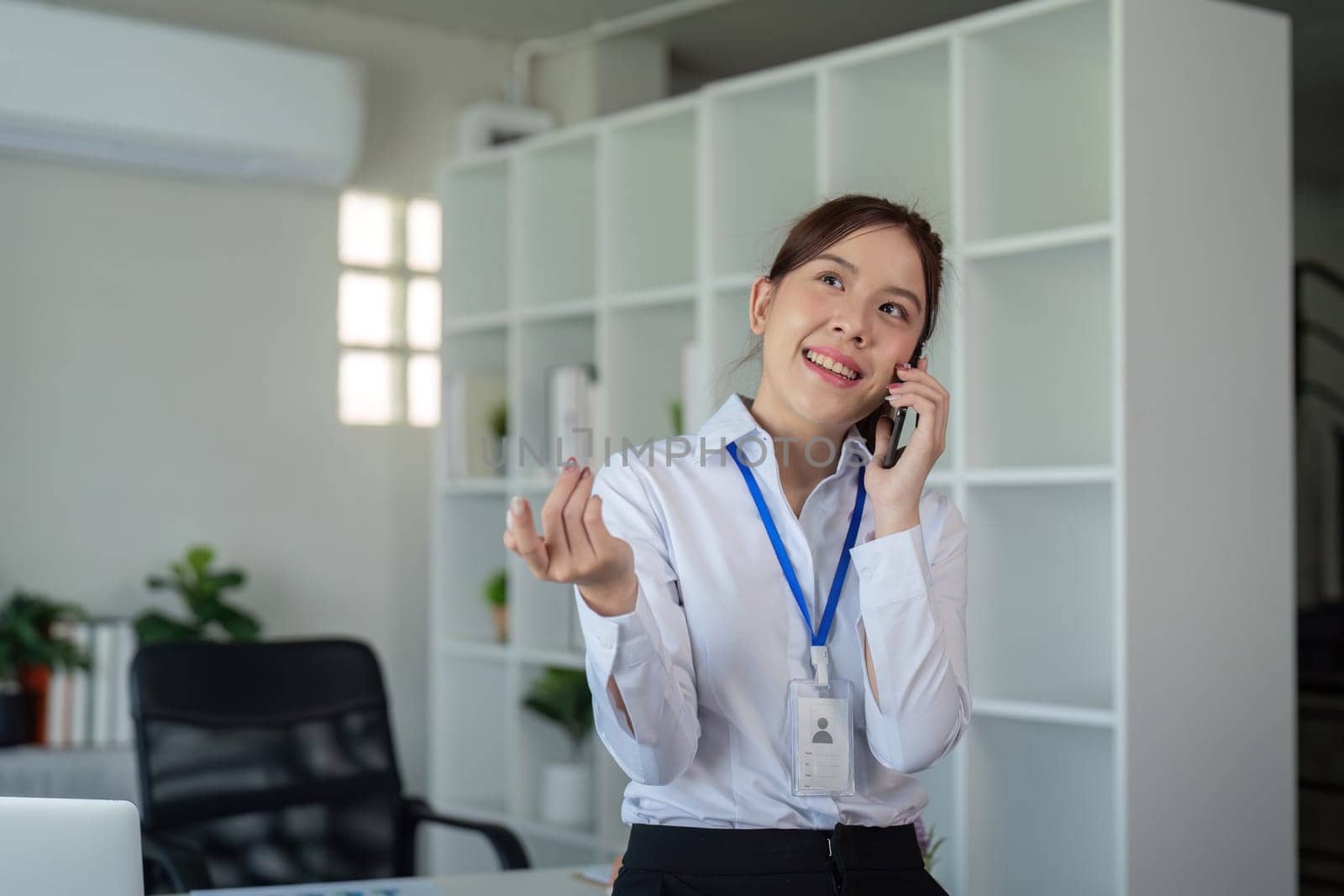 Attractive young business woman professional talking on the mobile phone and standing at working place in office by nateemee