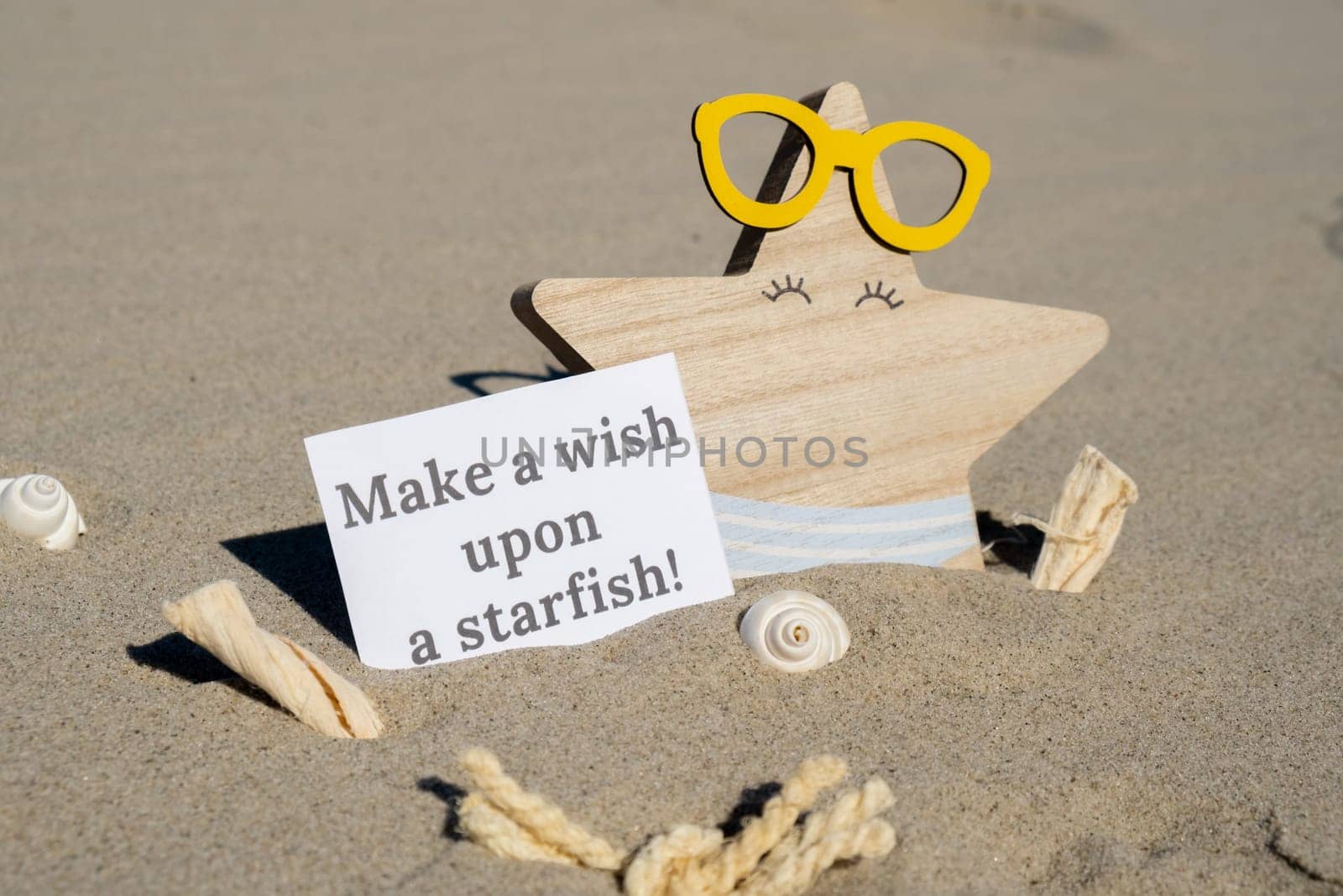 MAKE A WISH UPON A STARFISH text on paper greeting card on background of funny starfish in glasses summer vacation decor. Sandy beach sun coast. Holiday concept postcard. Getting away Travel Business concept