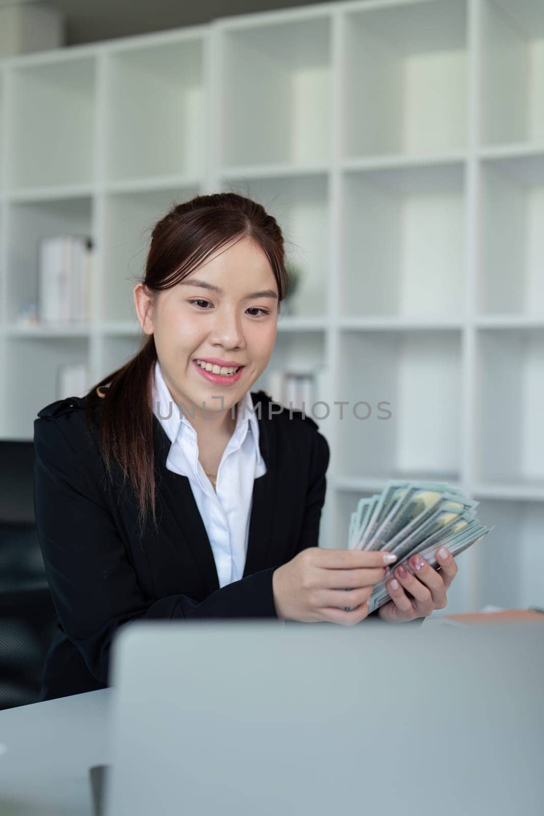 Businesswoman or financial bookkeeper holding bundle of money dollar for payment salary and income. entrepreneur counting money cash count salary profit finance at office by nateemee