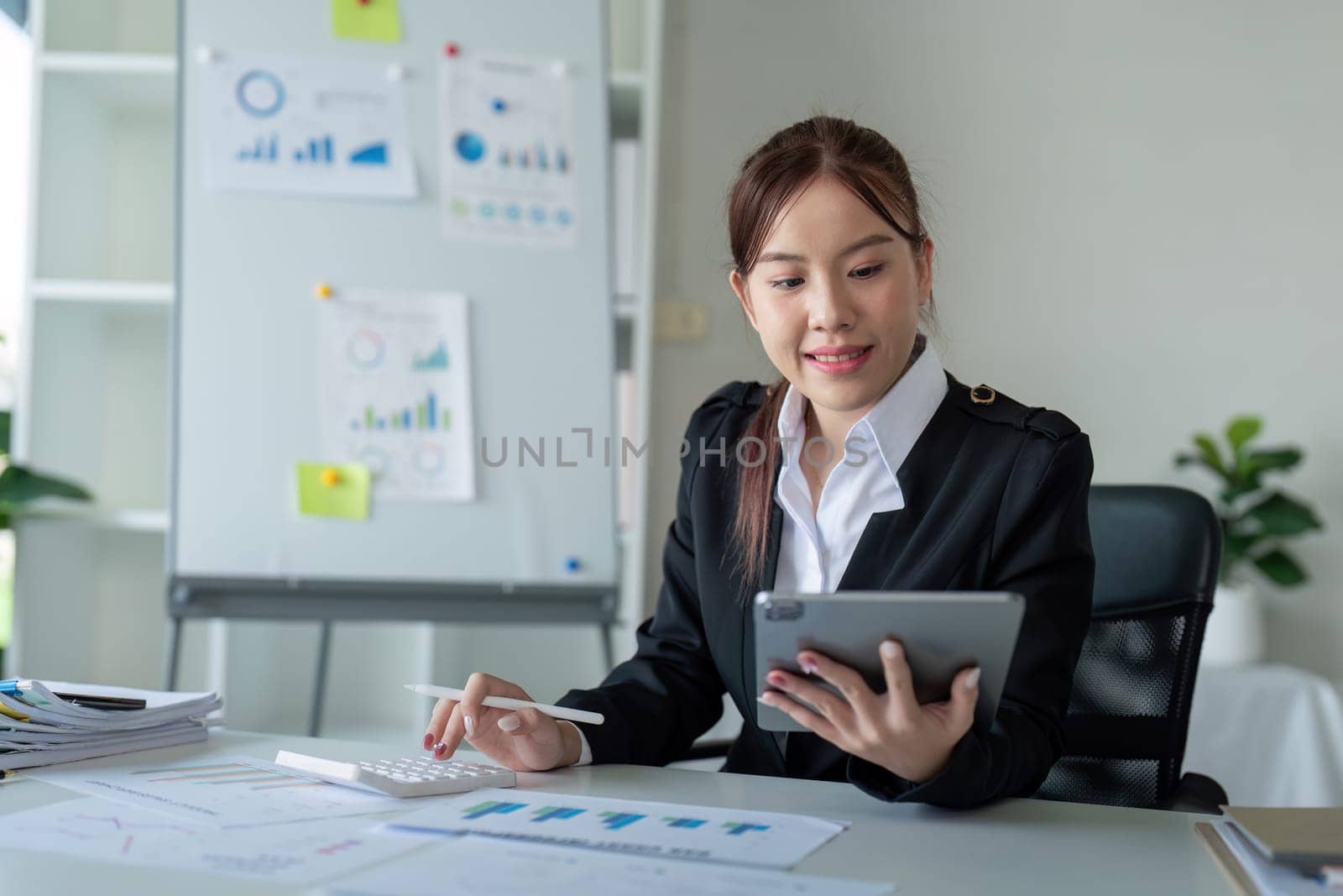 Businesswoman in office using tablet computer, audit documents and financial analysis, business people concept by nateemee