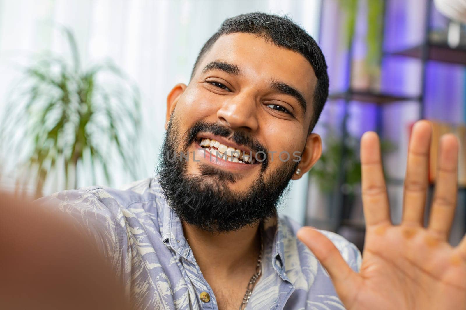 POV view of Indian young man blogger taking selfie on smartphone communicating video call online with subscribers recording stories for social media. Bearded Arabian guy holding mobile phone with hand
