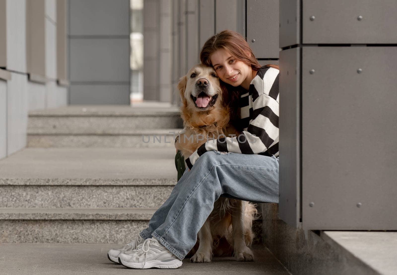 Teen Girl With Golden Retriever Sits In City During Spring