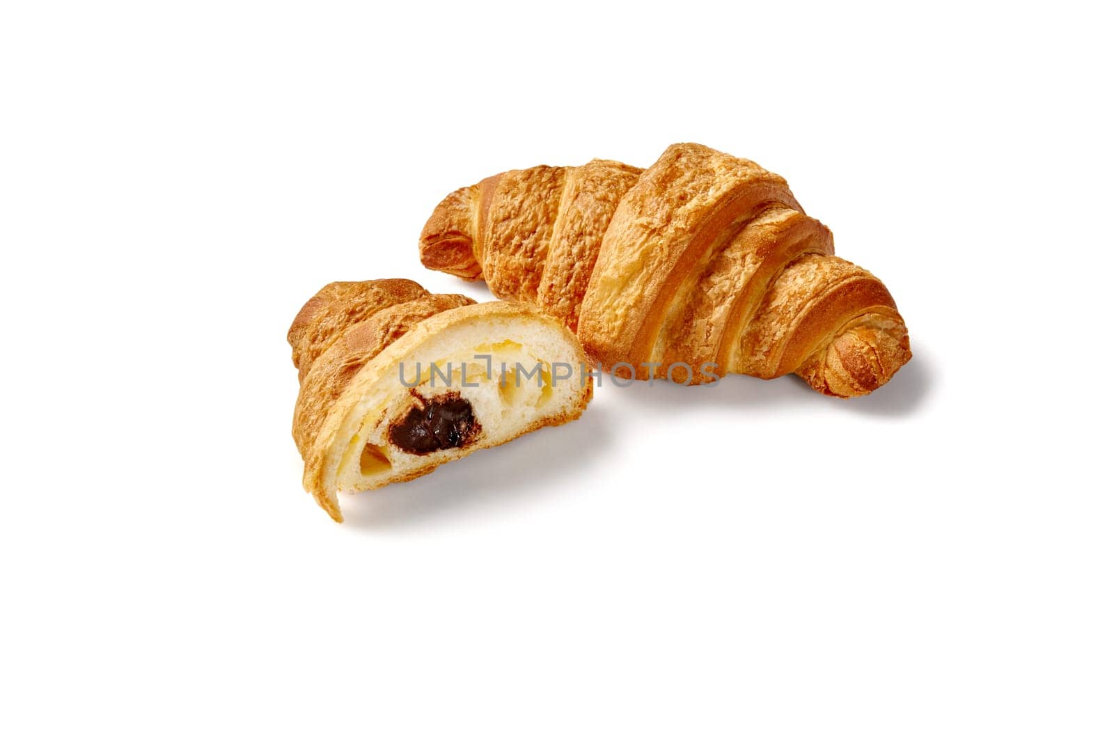 Whole and sliced gourmet fluffy croissants with rich chocolate cream filling, isolated on white background. French style viennoiserie pastry