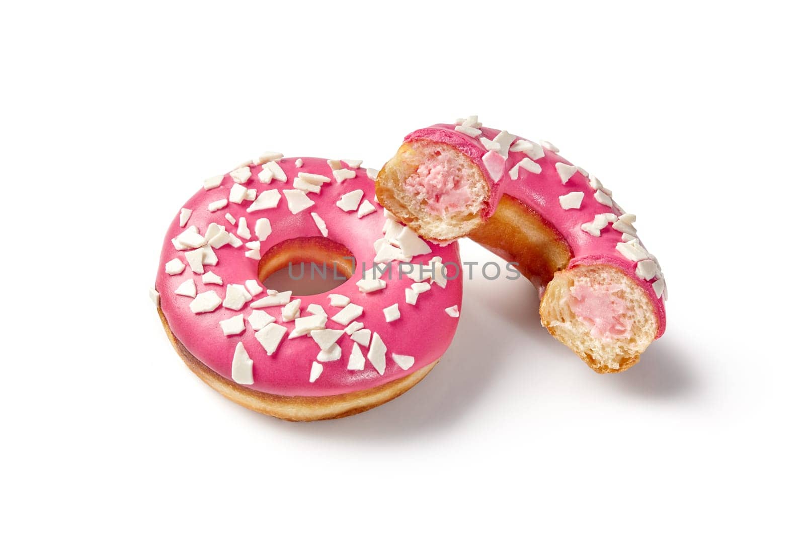 Appetizing soft fluffy donuts with creamy berry filling and vibrant pink icing sprinkled with white chocolate chips. Popular confectionery