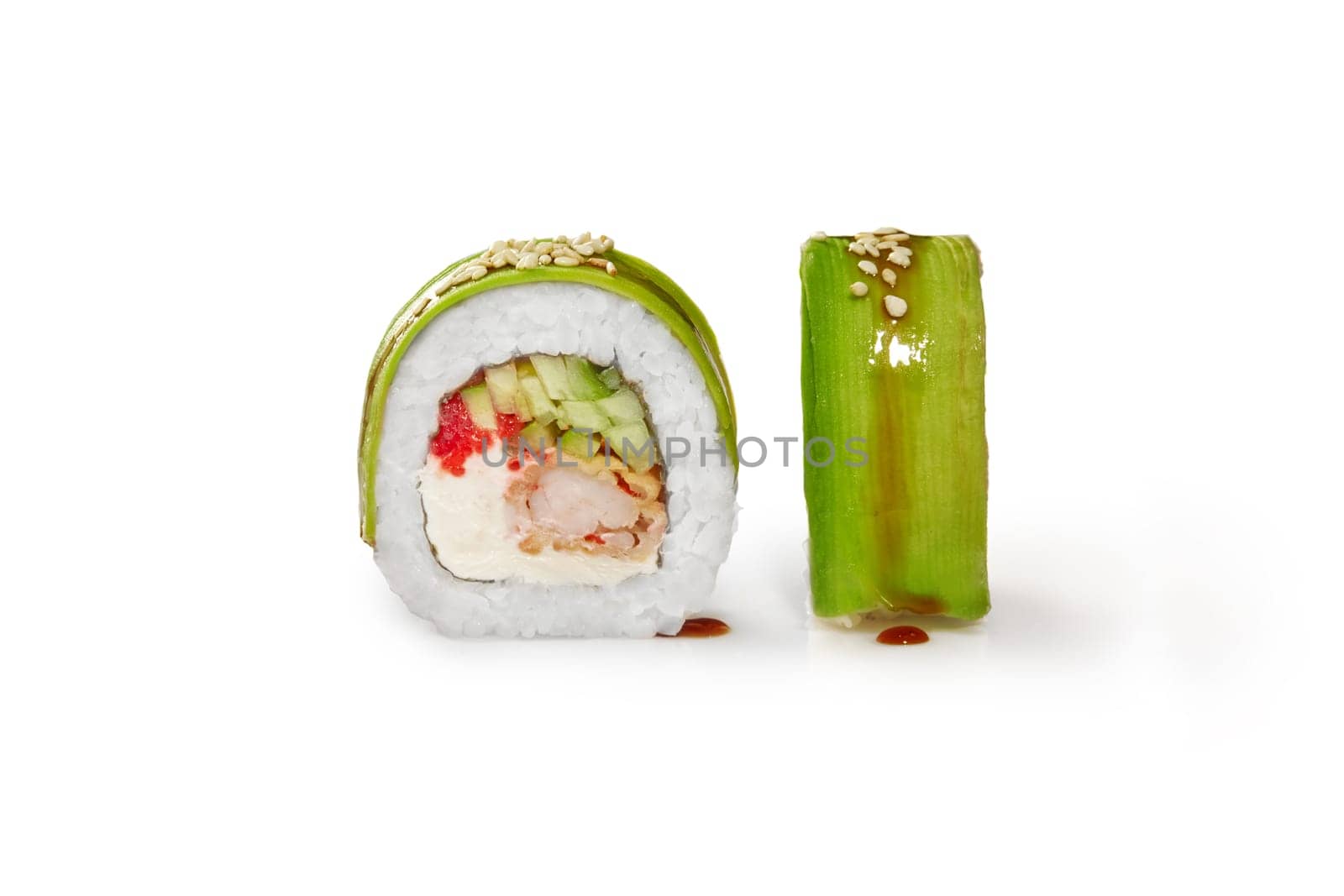 Closeup of appetizing sushi roll filled with tempura shrimp, cream cheese, cucumber and tobiko roe wrapped in thin avocado slices, isolated on white background