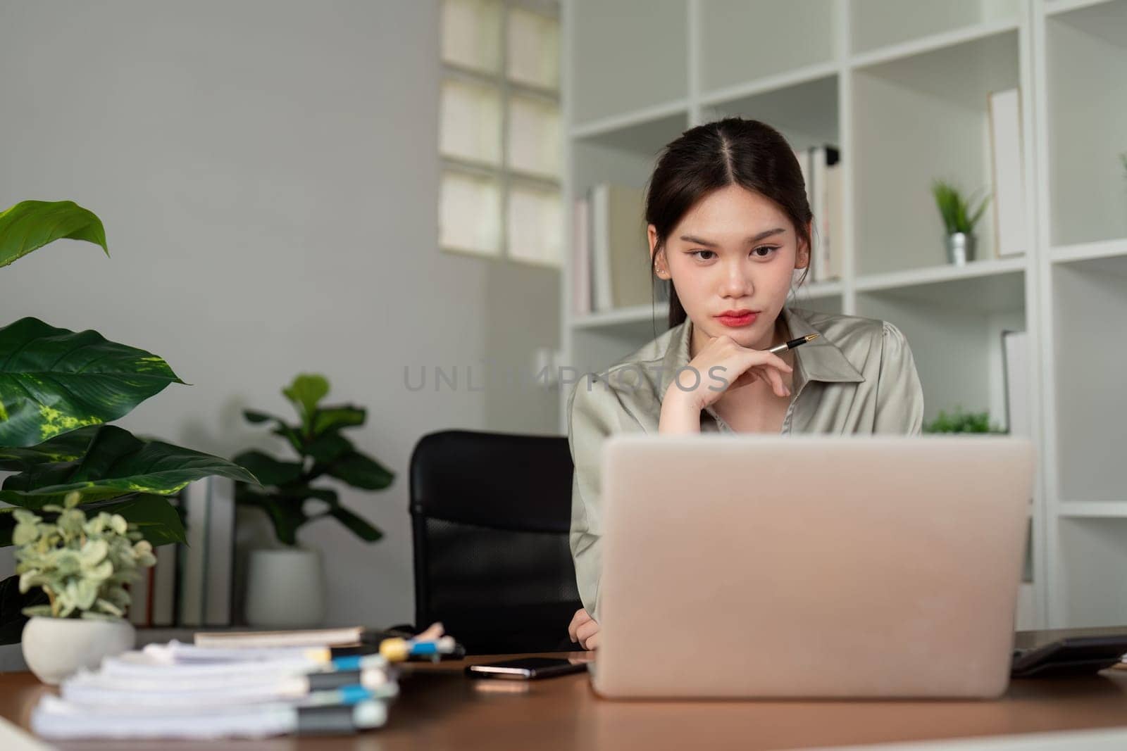 Business woman working in office checking documents. Woman accounting executive using laptop reading paper file financial report, tax invoice.