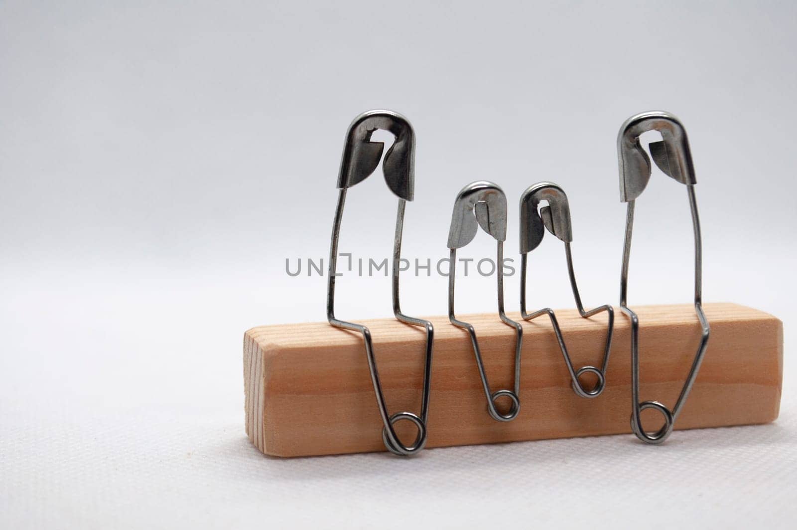 Model safety pin of family sitting on wooden block with customizable space for text.