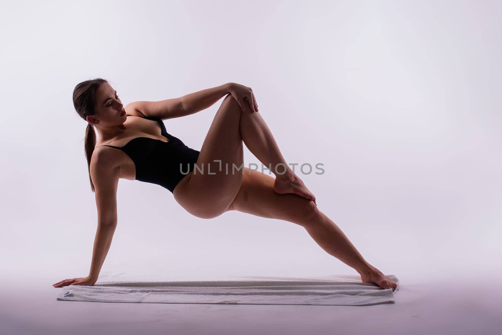 Athletic, beautiful, young female with sportive strong body training in bodysuit by Zelenin