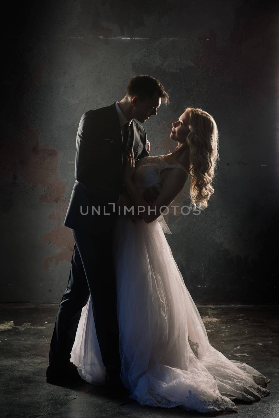 Cute wedding couple in the interior of a classic studio decorated. They kiss and hug each other. by Zelenin