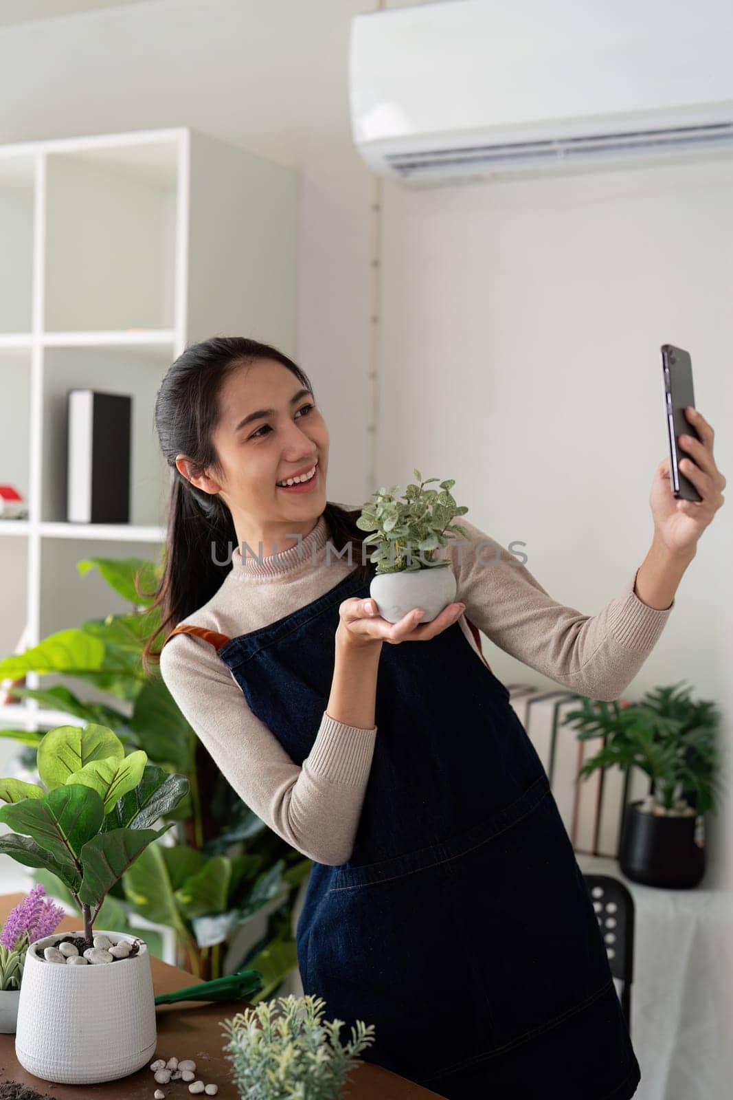 Hobby, asian young woman using mobile phone taking photo of pot, houseplant with dirt soil on table at home.