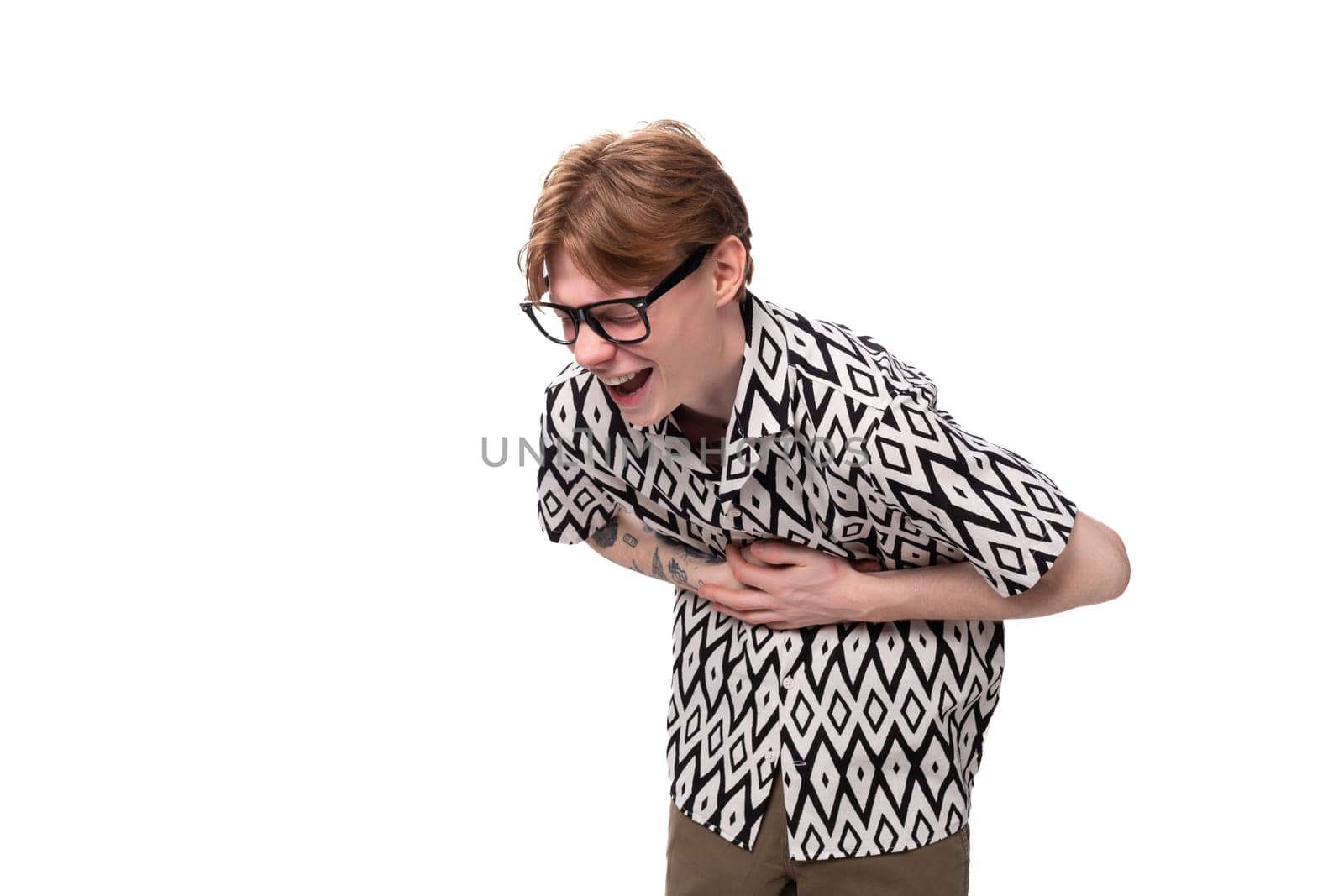 young laughing caucasian guy with red hair in glasses and a summer shirt on a white background with copy space.