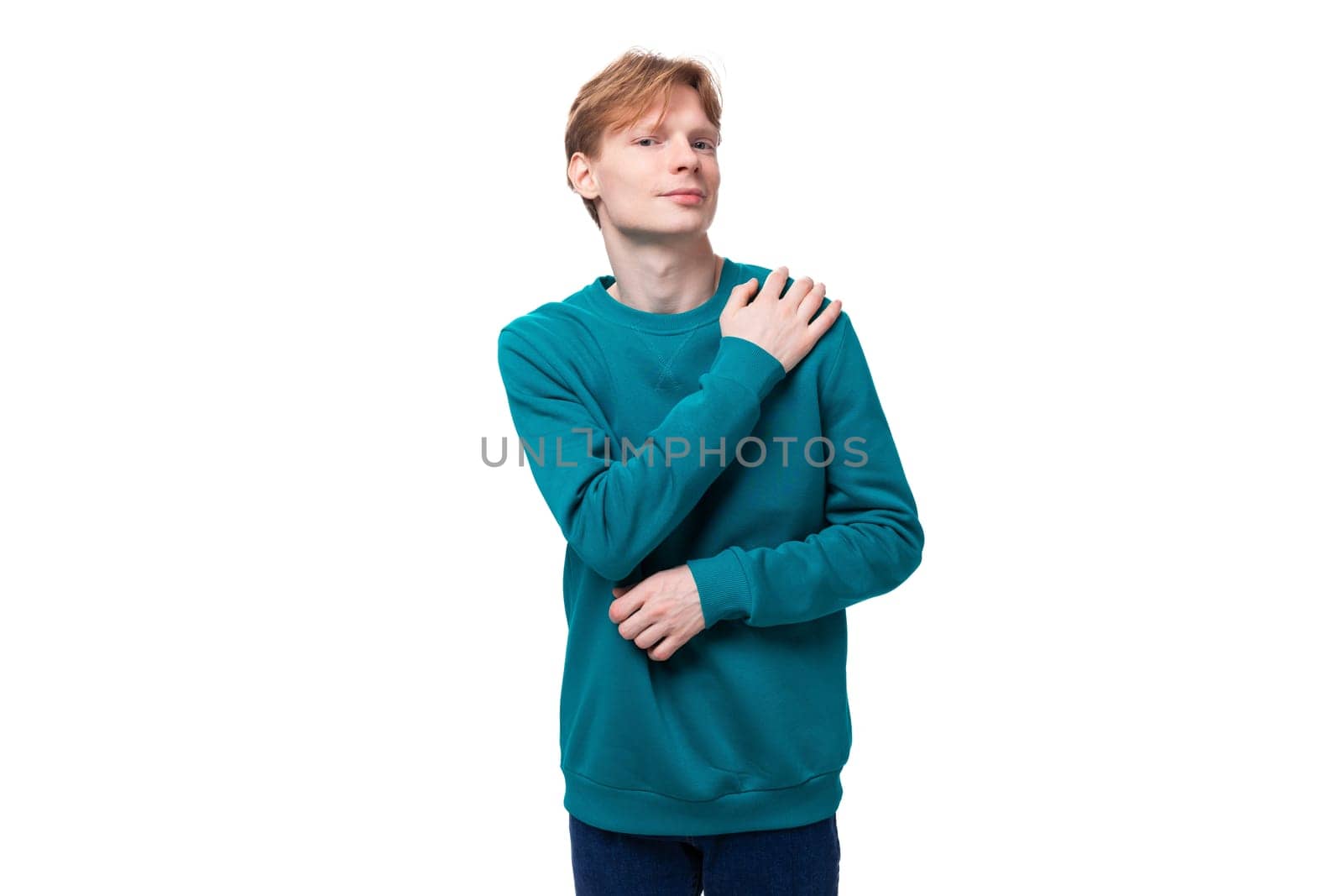 portrait of a cute caucasian young red-haired guy dressed in a blue pullover.