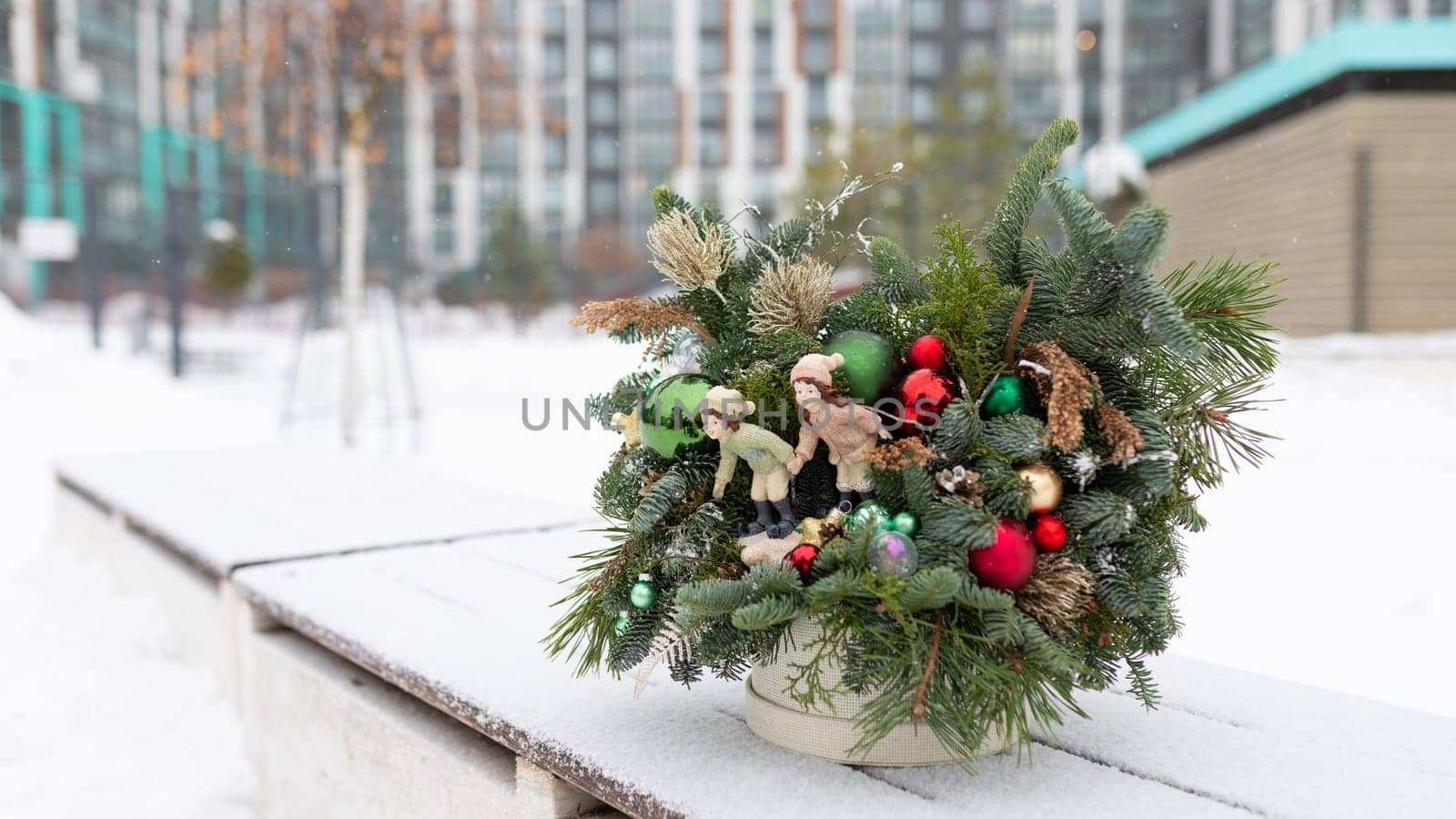 A potted plant adorned with Christmas decorations sits on a ledge. The decorations include ornaments, lights, and ribbons, adding festive cheer to the setting. The plant looks healthy and vibrant against the backdrop of the ledge.