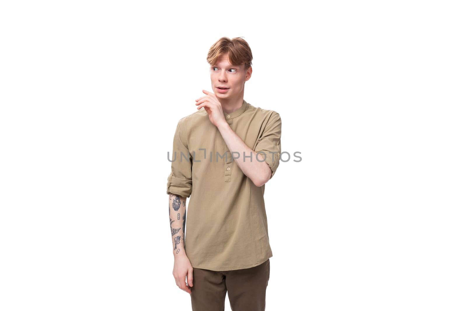 a young European guy with red hair is dressed in a fashionable beige shirt and brown trousers by TRMK