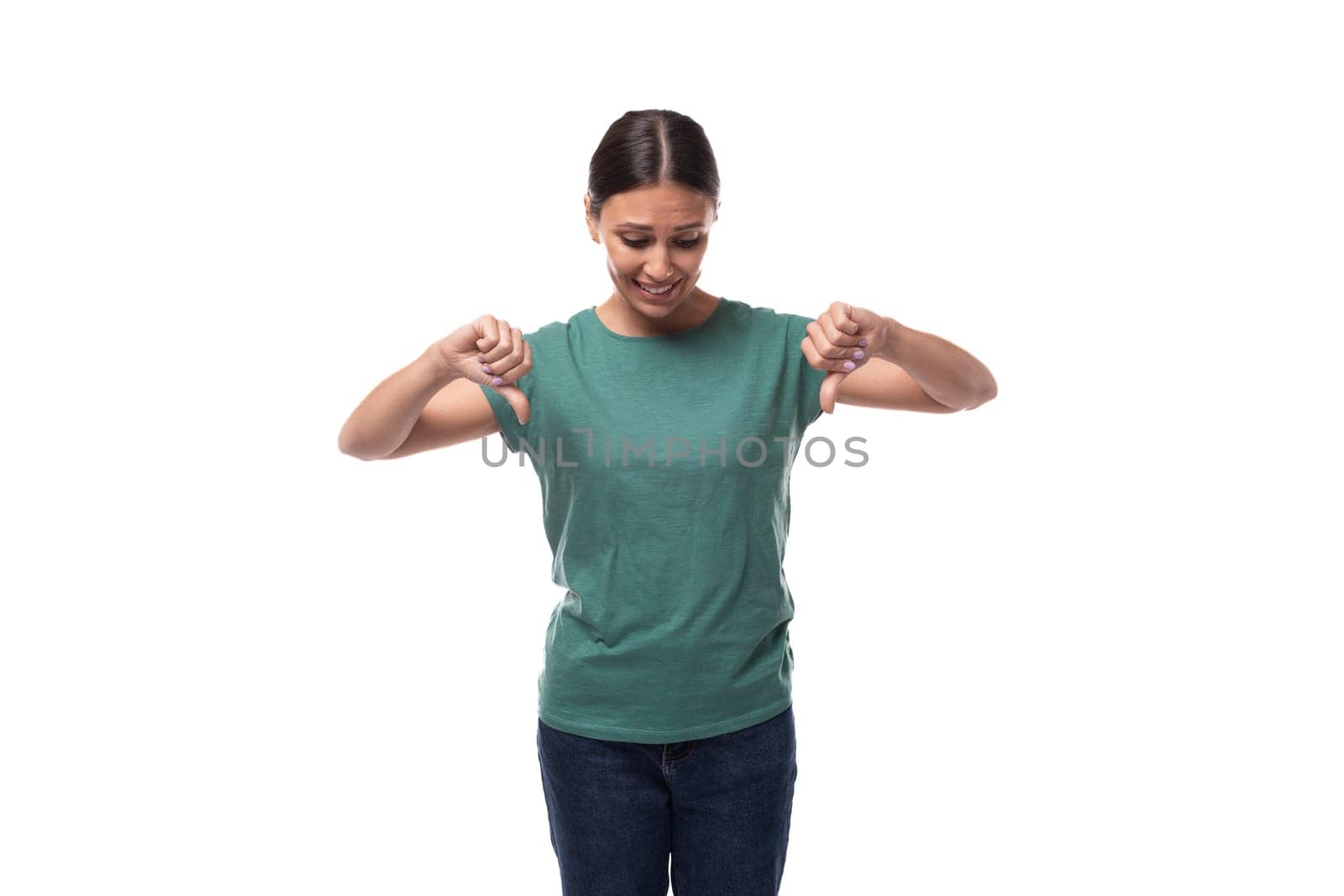 30 year old slender brunette woman with collected hair dressed in a green basic t-shirt works as a promoter and points with her hand at an empty space for advertising.