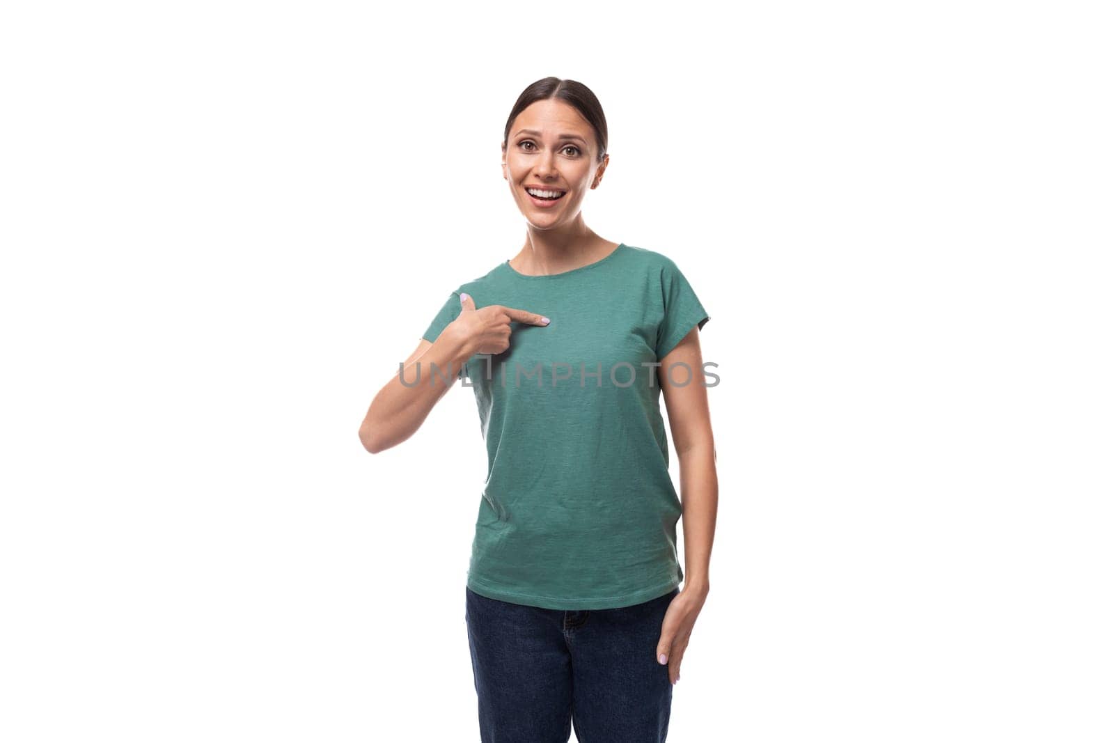 active smiling young caucasian brunette woman in a green t-shirt points with her hand at the space for advertising by TRMK