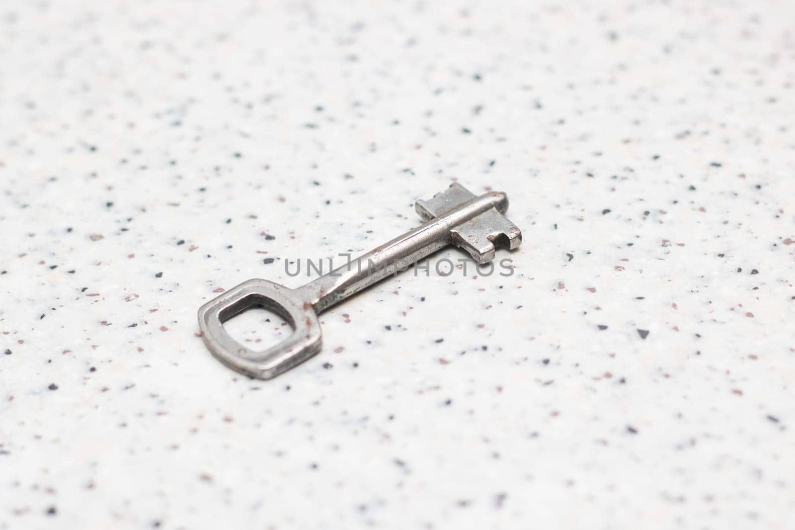 Close up of a nickel key on a white surface, a shiny metal accessory by Vera1703