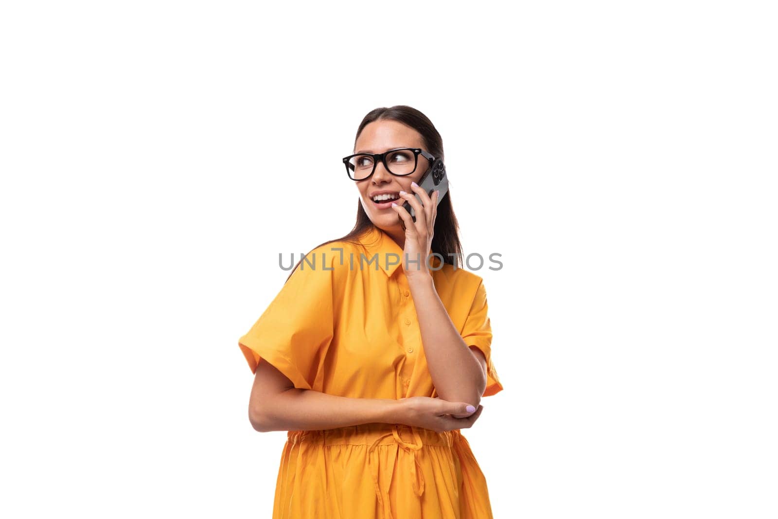 european young brunette lady dressed in an orange summer dress and glasses talking on the phone by TRMK