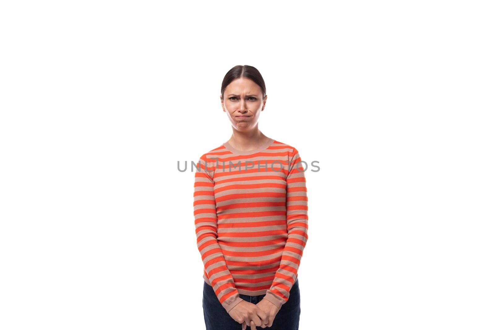 sullen young adult woman with black hair dressed in an orange sweater is angry.