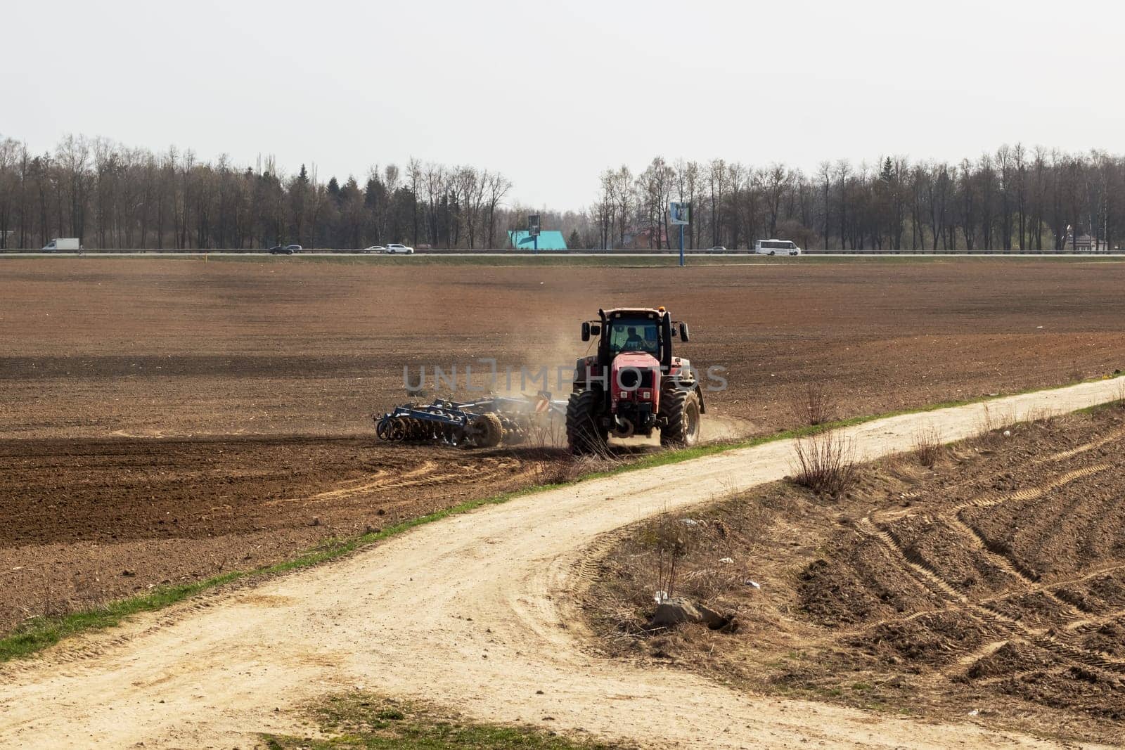 Red tractor is plowing a field closeup by Vera1703