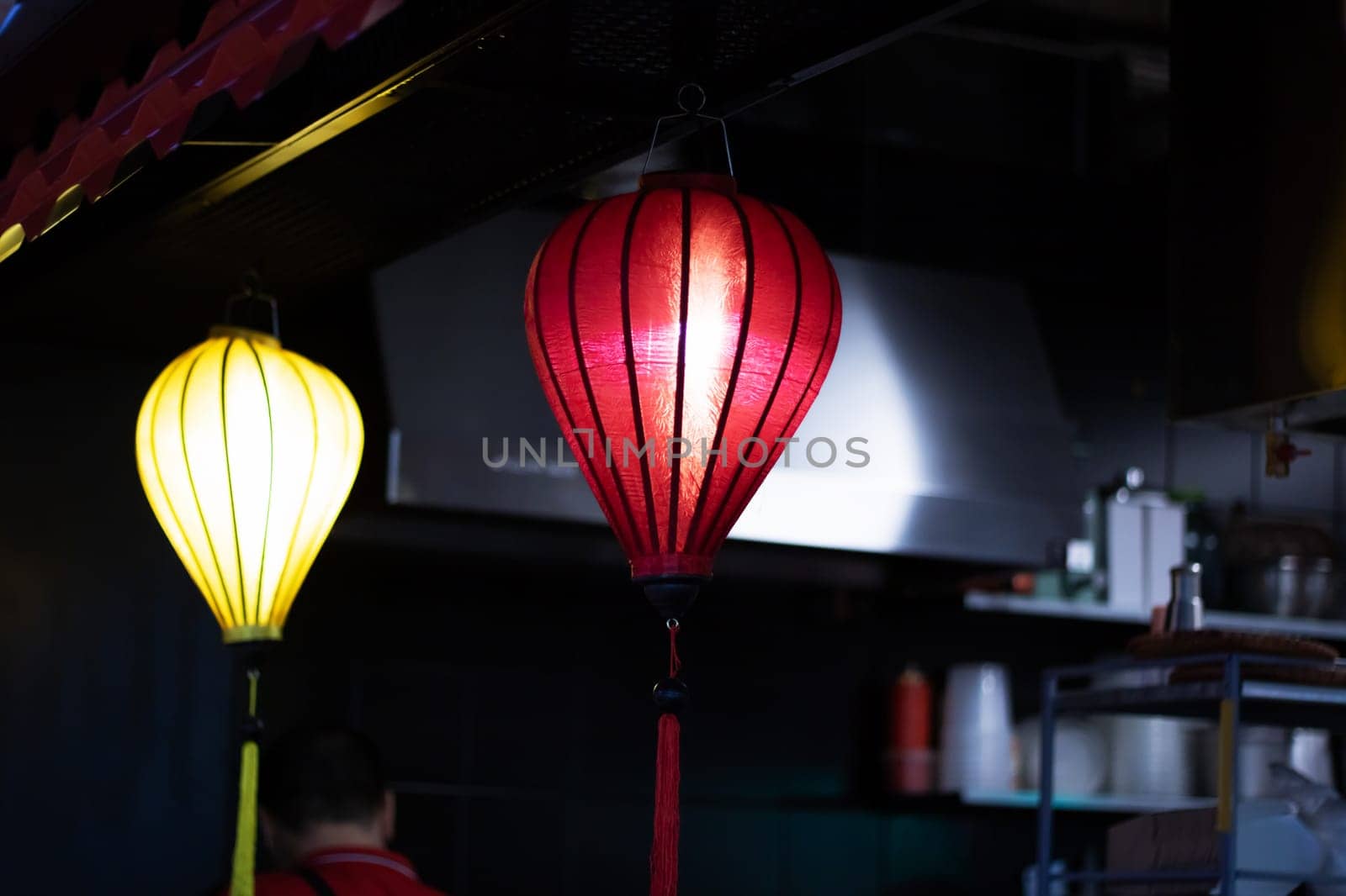 The restaurant is adorned with a row of colorful lanterns hanging from the ceiling, creating a vibrant atmosphere in the room